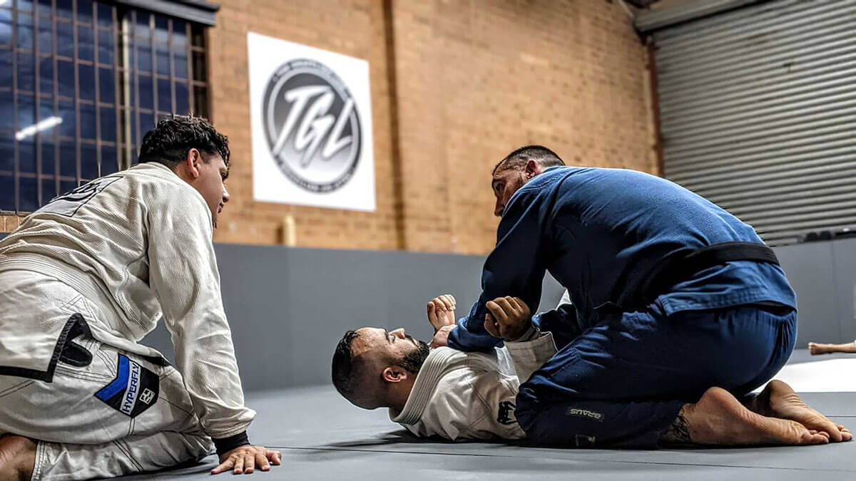 the grappling lab brazilian jiu jitsu prestons instructor explaining technique to 2 male students